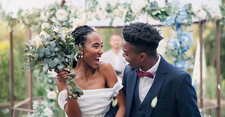A bride and groom smile at each other 